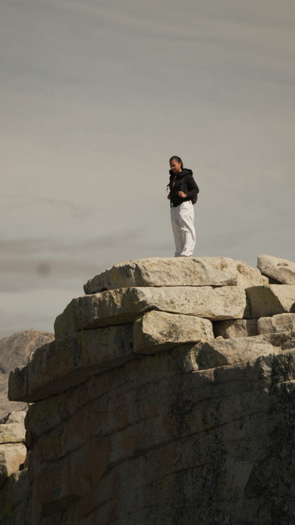 A woman standing at the summit of Half Dome