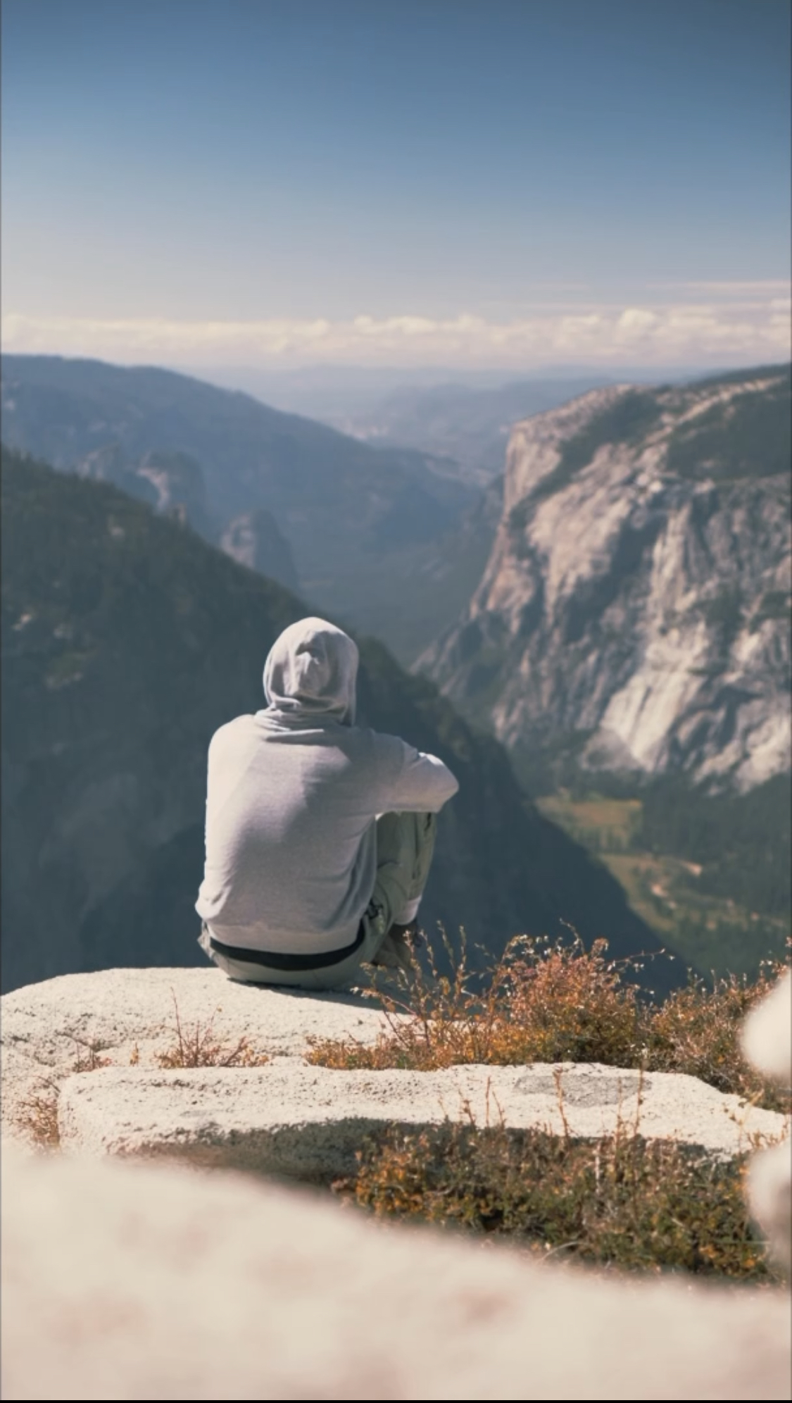 A lone figure sitting atop the Half Dome